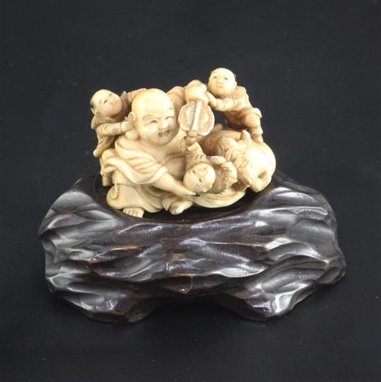 A Japanese ivory okimono of Hotei and three boys, signed Ikkosai, Meiji period, 4.6cm, wood stand